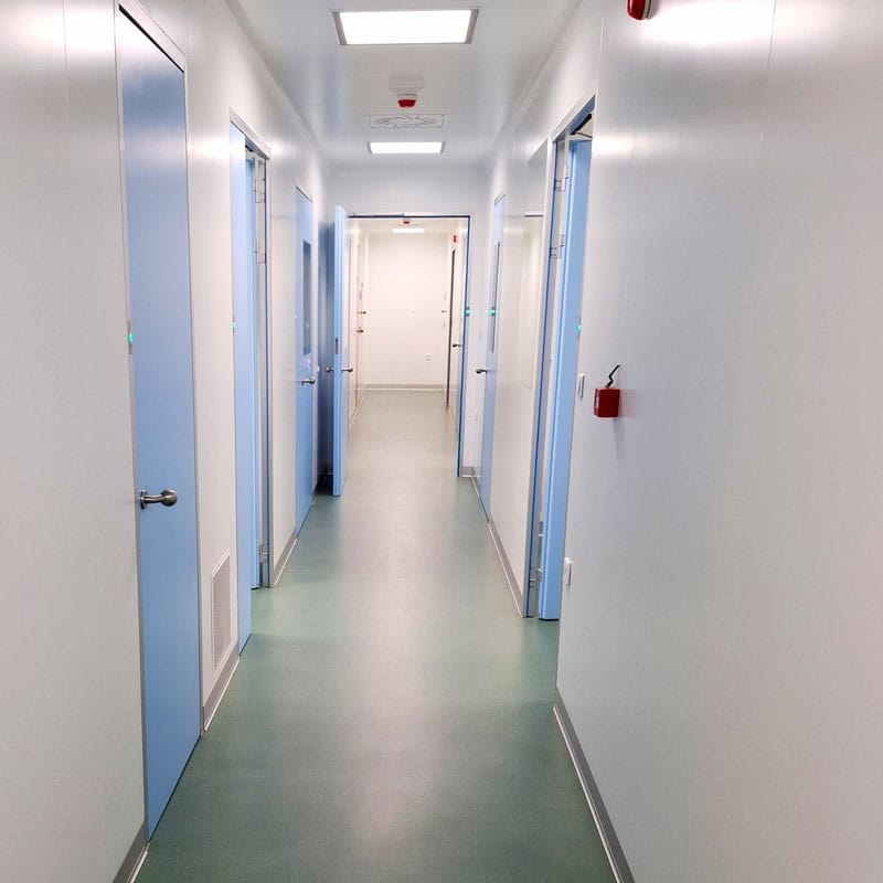 Hodnik u čistim prostorijama sa plavim vratima i LED rasvetom u farmaceutskoj proizvodnji