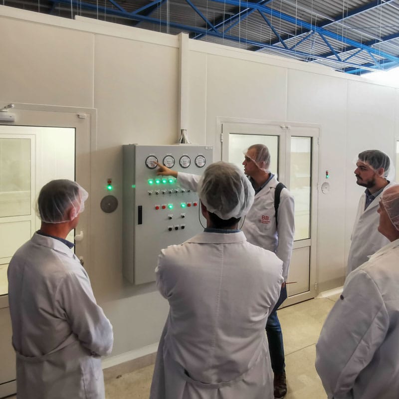 Inženjeri u zaštitnim mantilima prate očitavanja na kontrolnoj tabli u farmaceutskoj čistoj sobi