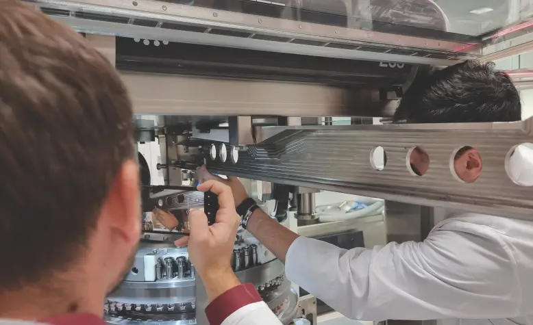 Tehničari podešavaju industrijsku mašinu u proizvodnom pogonu.