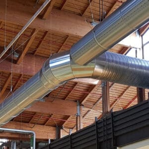 Perforirani kružni SpiroJet ventilacioni kanal u industrijskom objektu sa drvenim plafonom